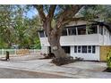 Beautiful two-story home featuring mature tree, white picket fence, and a gravel patio with picnic table at 4705 Hollingsworth Ave, Sarasota, FL 34233