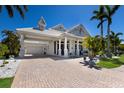 Beautiful exterior elevation featuring a three-car garage, and light gray exterior with meticulous landscaping and lush palm trees at 541 Fore Dr, Bradenton, FL 34208