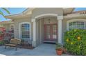 Inviting front entry with double doors, columns, manicured bushes, bench, and lush landscaping surrounding the entrance at 5518 Eastwind Dr, Sarasota, FL 34233