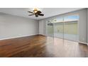 Bright bedroom with hardwood floors, a ceiling fan, a door, and sliding glass doors to the patio at 7665 Bergamo Ave, Sarasota, FL 34238