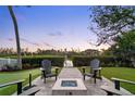 Cozy backyard with a fire pit, comfortable Adirondack chairs, manicured lawn and a peek at the waterfront at 8258 Midnight Pass Rd, Sarasota, FL 34242