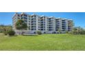 Sprawling condominium featuring a lush green lawn, tropical landscaping, and multi-level balconies at 8735 Midnight Pass Rd # 301B, Sarasota, FL 34242