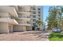 Exterior of condo featuring private balconies, brick drive, mature trees, and covered parking at 8735 Midnight Pass Rd # 301B, Sarasota, FL 34242