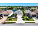 An aerial view of a single-story home with a well manicured front yard, lush landscaping and beautiful water view at 12717 Deep Blue Pl, Bradenton, FL 34211