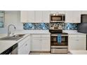 Kitchen with stainless steel appliances, white cabinets, quartz counters and a colorful backsplash at 17626 Gawthrop Dr # 305, Bradenton, FL 34211