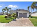 Charming single-story home featuring lush landscaping, brick driveway, and attached two car garage at 25325 Longmeadow Dr, Punta Gorda, FL 33955