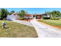 Exterior view of a charming home with a well-kept lawn, mature trees, and a long driveway for multiple cars at 4008 Cape Vista Dr, Bradenton, FL 34209