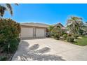 Attractive single-story home with a spacious driveway, tropical landscaping, and a two-car garage at 457 Lake Of The Woods Dr, Venice, FL 34293