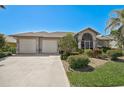 Inviting single-story home with a large driveway, two-car garage, and beautifully landscaped front yard at 457 Lake Of The Woods Dr, Venice, FL 34293