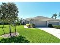 Attractive gray home with a well-manicured lawn, mature landscaping, and a two-car garage at 5223 Chase Oaks Dr, Sarasota, FL 34241