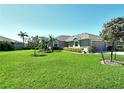 Well-maintained front yard featuring lush green grass, mature landscaping, and a charming gray home at 5223 Chase Oaks Dr, Sarasota, FL 34241