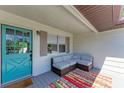 Inviting porch area with a comfy couch, colorful rug, and a bright blue front door at 5311 San Jose Dr, Sarasota, FL 34235