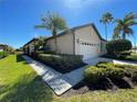 A sunny view of a single-story house featuring a lush green lawn, well-kept bushes, and a two-car garage at 11331 Bertolini Dr, Venice, FL 34292