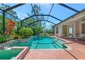 Relaxing screened-in pool area featuring tropical landscaping, a spa, and outdoor seating at 11419 Pine Lilly Pl, Lakewood Ranch, FL 34202