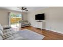 Inviting living room with hardwood floors, ceiling fan, comfortable seating, and sliding glass door to backyard at 1200 74Th N St, St Petersburg, FL 33710