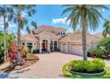 Elegant Mediterranean-style home featuring a tile roof, paver driveway, and lush tropical landscaping at 13708 Red Rock Pl, Lakewood Ranch, FL 34202