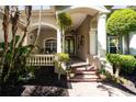 Charming home entryway featuring a brick path, columns, mature landscaping, and a decorative front door at 13955 Pine Woods E Ln, Sarasota, FL 34240
