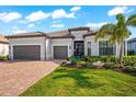 Charming single-story home featuring a tile roof, a brick paver driveway, and a two-car garage at 17916 Northwood Pl, Lakewood Ranch, FL 34202
