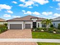 Charming single-story home with a tile roof, three-car garage, and vibrant landscaping, creating a welcoming entrance at 17916 Northwood Pl, Lakewood Ranch, FL 34202