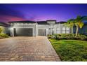 Elegant stucco home featuring a tile roof, three-car garage, and lush landscaping, offering curb appeal at 17916 Northwood Pl, Lakewood Ranch, FL 34202