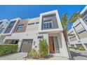 Contemporary exterior features a garage, stylish front door, complemented by manicured greenery and a palm tree at 232 Cosmopolitan Ct, Sarasota, FL 34236