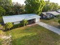 An aerial view of a home with a metal roof, a screened porch, and a well-maintained lawn in a quiet neighborhood at 2525 Arapaho St, Sarasota, FL 34231