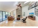 Inviting living room with a stone fireplace, hardwood floors, and a vaulted ceiling with a fan at 3111 Bayou Sound, Longboat Key, FL 34228