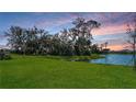 Picturesque backyard view featuring a serene lake surrounded by lush greenery at sunset at 8918 Waxwing Way, Parrish, FL 34219