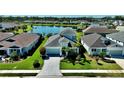 Expansive single-Gathering home with a paver driveway, surrounded by lush landscaping and a tranquil lake at 10527 Falling Leaf Ct, Parrish, FL 34219