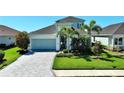 Charming single-Gathering home featuring a well-manicured lawn, mature palm trees, and a two-car garage at 10527 Falling Leaf Ct, Parrish, FL 34219