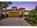 Charming single-Gathering home with lush landscaping and a brick-paved driveway at dusk at 12711 Del Corso Loop, Bradenton, FL 34211