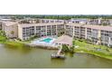 Scenic aerial view of lakeside condos featuring a pool, clubhouse, and private dock for outdoor enjoyment at 3821 Lake Bayshore Dr # H-507, Bradenton, FL 34205