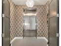 Hallway leading to a private elevator with decorative wallpaper and designer lighting fixture at 4765 Gulf Of Mexico Dr # B202, Longboat Key, FL 34228