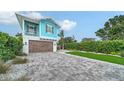 View of the property's paver driveway leading to a well-maintained two-story home with a wooden garage door at 5930 Briarwood Ave, Sarasota, FL 34231