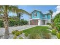 Charming light blue two-story home with a paver driveway, lush landscaping, and a garage at 5930 Briarwood Ave, Sarasota, FL 34231
