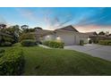 Charming home with manicured lawn, mature landscaping, and attached garages at dusk at 7205 Wood Creek Dr # 16, Sarasota, FL 34231