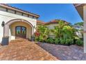 Ornate wood doors framed by arched stone entryway and lush, tropical landscaping at 909 143Rd Ne St, Bradenton, FL 34212