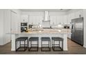 A modern kitchen features an island with barstool seating, stainless appliances, and white cabinetry at 15916 Sugar Hill Dr, Punta Gorda, FL 33982