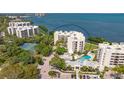 An aerial view of a waterfront condo complex featuring a swimming pool and tennis courts at 2020 Harbourside Dr # 454, Longboat Key, FL 34228