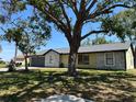 Charming single-story home with a gray roof and a well-manicured lawn, shaded by mature trees at 2816 N Lockwood Meadows Blvd, Sarasota, FL 34234