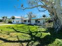 Single story house with blue tarp on roof, yard and mature shade tree at 305 59Th St, Holmes Beach, FL 34217