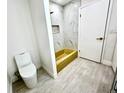Bathroom featuring modern toilet, gold fixtures, and unique gold bathtub with shower at 3320 Riviera Dr, Sarasota, FL 34232