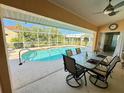 Covered patio with a dining set overlooking a screened in-ground swimming pool with a view of the backyard at 417 Firethorn Ave, Englewood, FL 34223