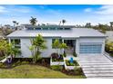 Beautiful modern home with a metal roof, elegant landscaping, and a stylish glass garage door at 600 De Narvaez Dr, Longboat Key, FL 34228