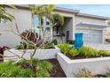 Landscaped front yard featuring a blue water feature, lush plants, and palm trees, adding curb appeal at 600 De Narvaez Dr, Longboat Key, FL 34228