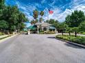 View of the secure community gate with manicured landscaping and an American flag waving in the breeze at 6605 Waters Edge Way, Lakewood Ranch, FL 34202