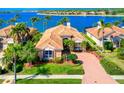 Waterfront home showcasing a tile roof, brick driveway, and meticulously manicured landscaping at 6605 Waters Edge Way, Lakewood Ranch, FL 34202