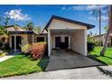 Single-story home with a covered parking area, landscaped front yard and blue sky at 6946 Woodwind Dr # 2, Sarasota, FL 34231