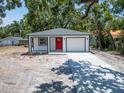 Single-story home with a bright red front door and an attached garage under a canopy of trees at 732 15Th E St, Bradenton, FL 34208