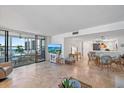 Open-concept living room, dining area, and balcony showcasing a light color palette and travertine floors at 8735 Midnight Pass Rd # 306B, Sarasota, FL 34242